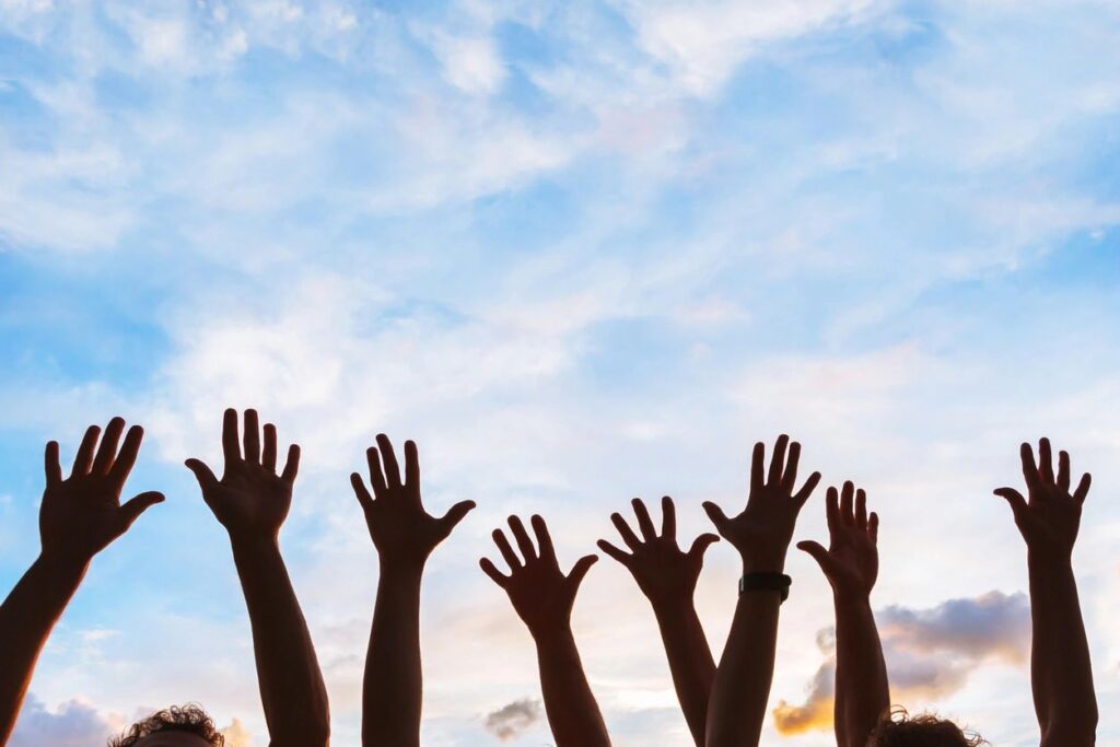 hands reaching up to the blue sky