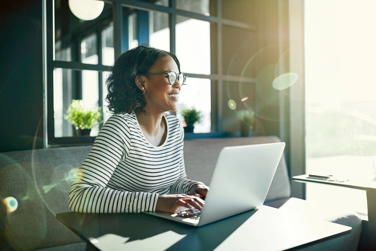 woman on computer at desk sun coming in window