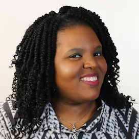 a women with dark curly hair smiling with a black and white shirt